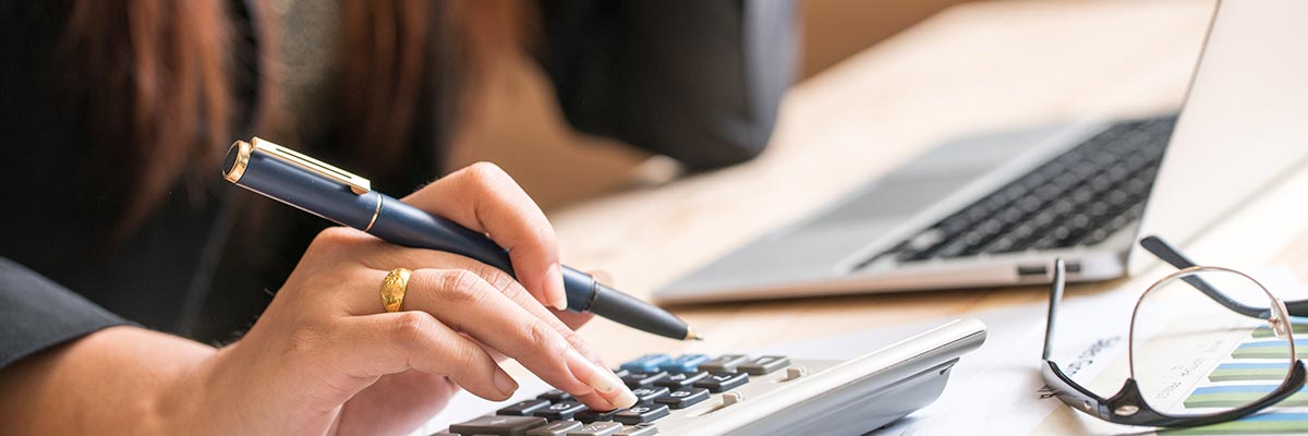 Woman working with calculator, pen, laptop and spreadsheets