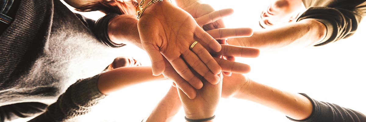 Circle of people putting their hands into the centre together