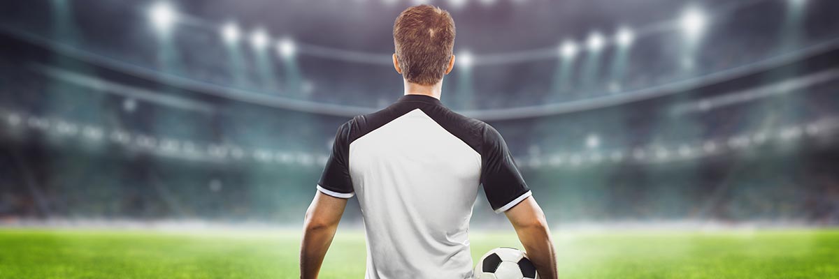 Lionel Messi, football under his arm, facing the field in a floodlit stadium