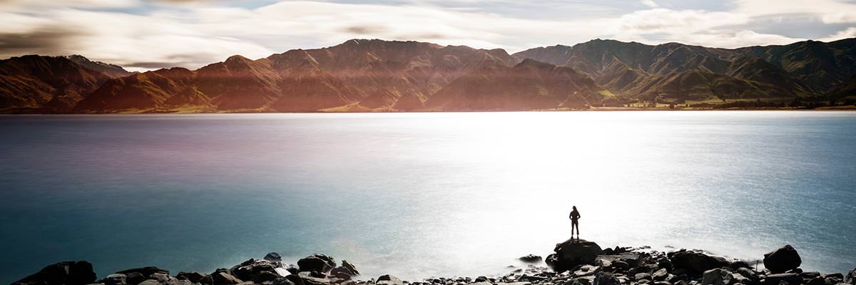 Woman standing on a rock overlooking Lake Hawea with hills beyond