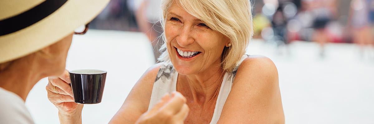 Two women drinking coffee together at a pavement cafe in Italy