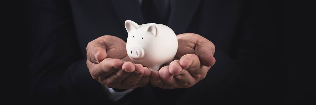 Man in a suit cradling a piggy bank in his hands