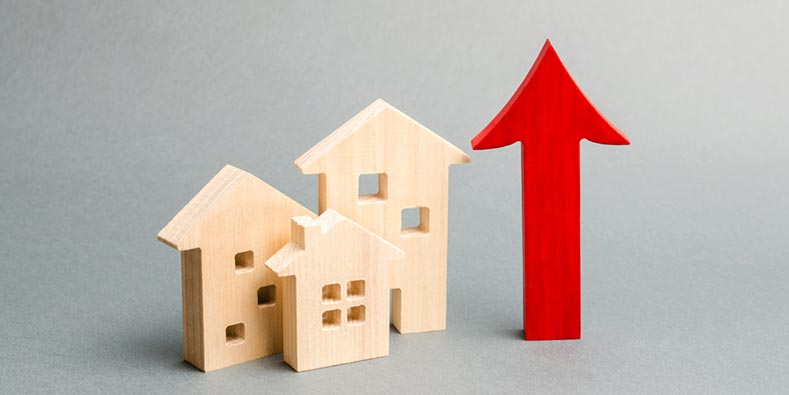 Little wooden houses next to a red arrow pointing upwards.