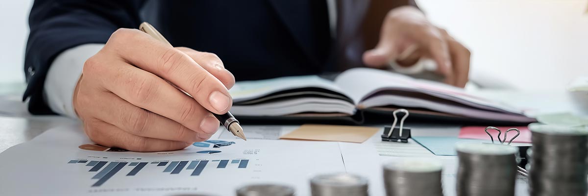 Financial planner with spreadsheets and graphs behind a stack of money