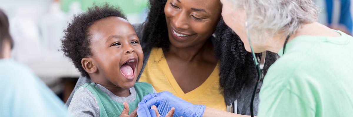 Volunteer doctor checking the heartbeat of a smiling African child