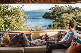 Couple relaxing at the bach, reading and looking out at the view