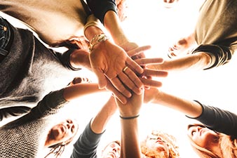 Circle of people putting their hands into the centre together
