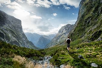 Tramper looking across a steep valley in the Fiordland National Park to the Southern Alps beyond