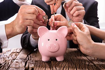 Many people putting coins into a piggy-bank