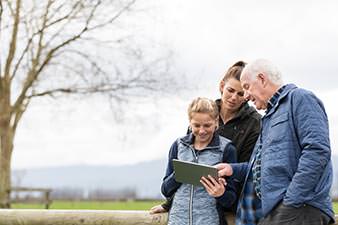 Three generations - grandfather, mother, daughter - looking at an iPad together